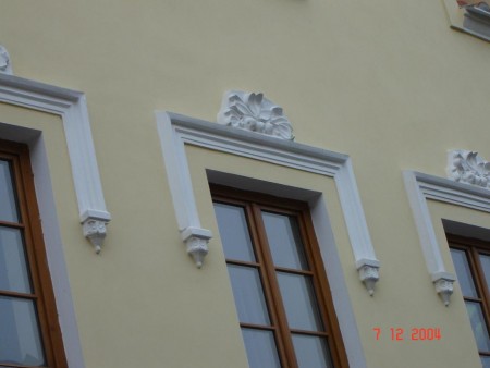 Detail nátěru fasády s bílými štukovými prvky v Lokti